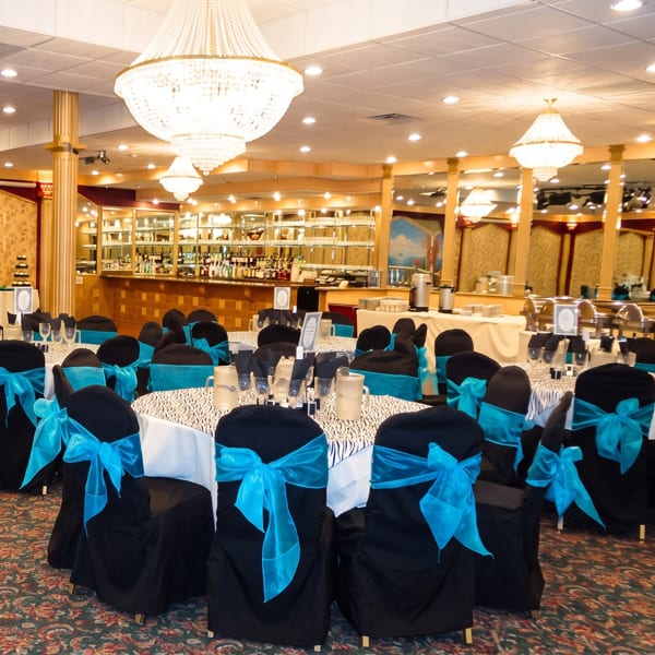 Elegant banquet hall with black chairs, turquoise bows, zebra-print tables, and a full bar.