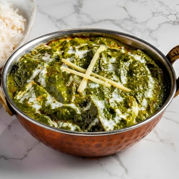 Palak Paneer, a vibrant green spinach and cheese curry, served with white rice on a marble surface.