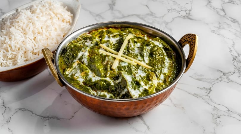 Palak Paneer, a vibrant green spinach and cheese curry, served with white rice on a marble surface.